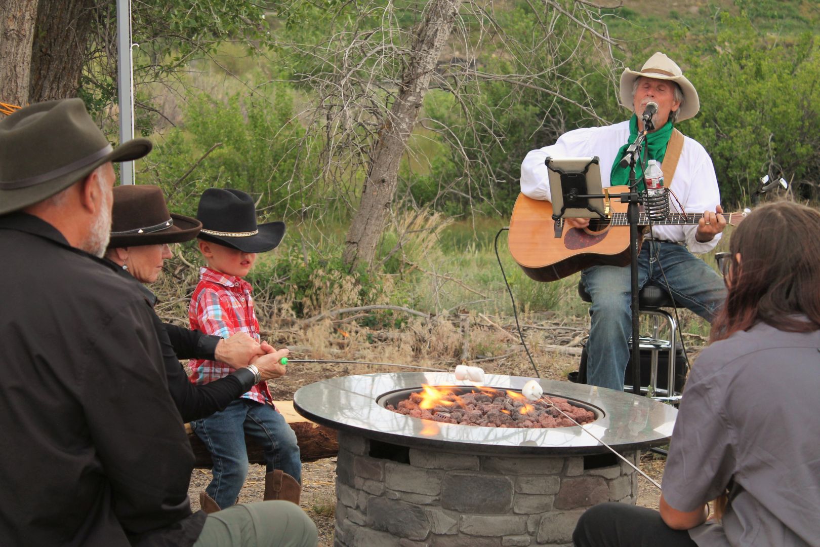 Cowboy playing a guitar and singing a song around a campfire
