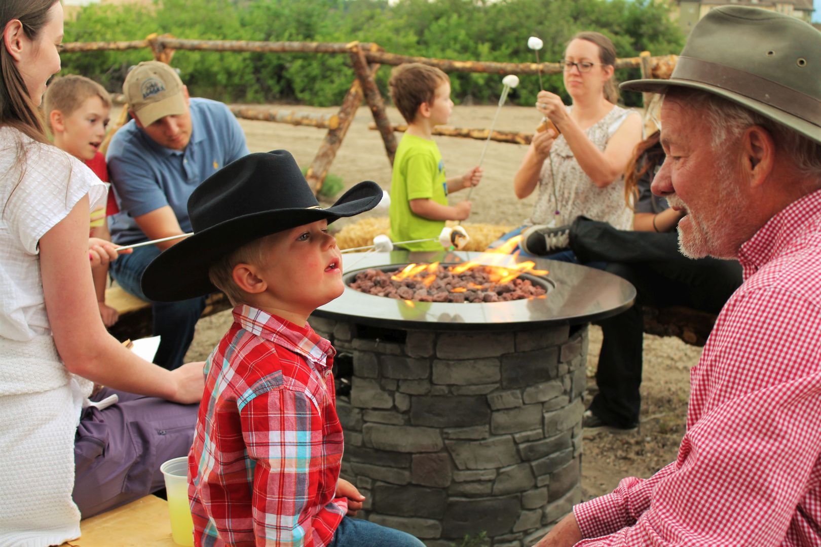 Boy in a cowboy hat and people roasting marshmellows