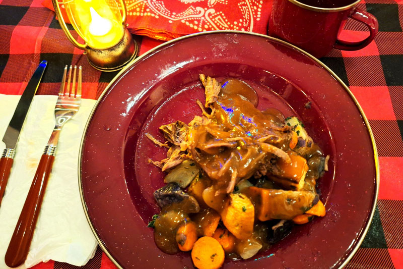 A plate full of beef stew on a checkered table cloth